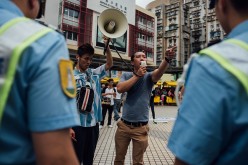 A protester shouts slogans as police stand guard on a street on May 1, 2015 in Macau. 