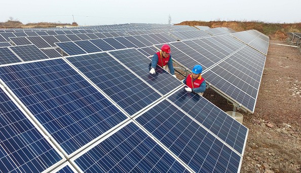 Workers check the grid-connected photovoltaic system built on an abandoned mine at Chihe Town in Chuzhou, Anhui Province.