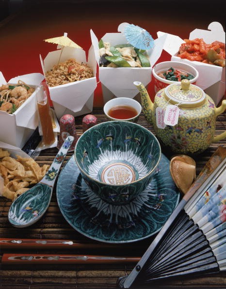 A display of Chinese take-out food and appropriate serving and eating items.