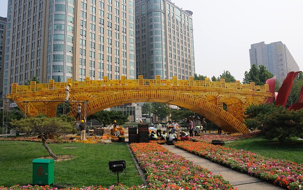 Workers install a golden flower bed called "Silk-Road on Golden Bridge."