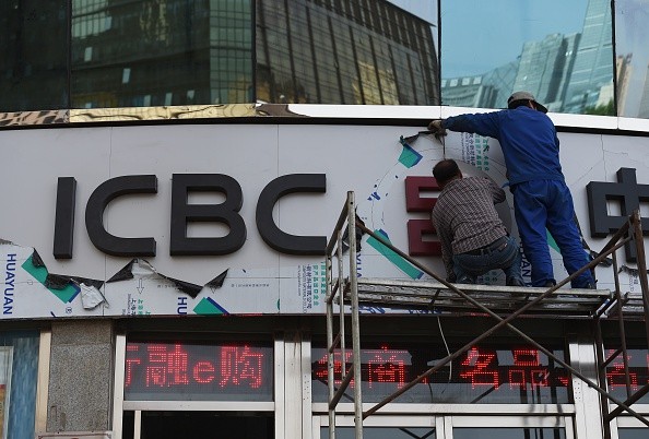 Workers install a sign above the entrance to a branch of the Industrial and Commercial Bank of China.