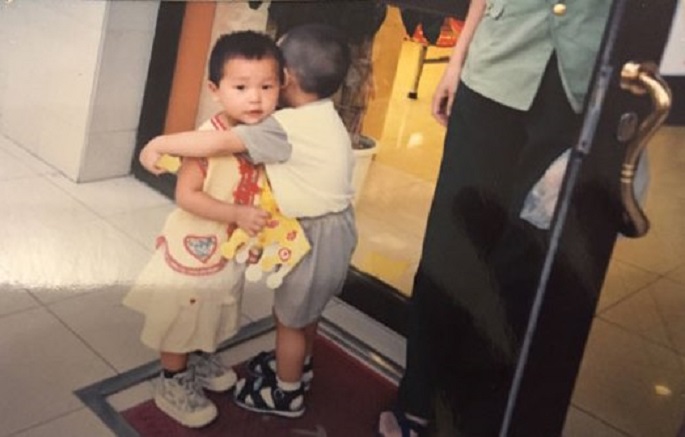A little boy gives a female kid a hug outside a cake shop in Wanxincun in Hedong District, Tianjin, in Aug. 1999. The grown-up girl now wants to know his identity.