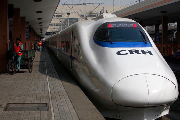 A worker pedals past a CRH (China Railway High-speed) bullet train at Hangzhou Railway Station.