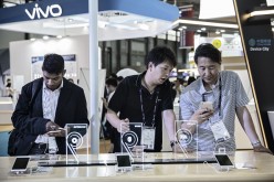 Attendees look at smartphones manufactured by Oppo and Vivo at the Mobile World Congress Shanghai in Shanghai, China.