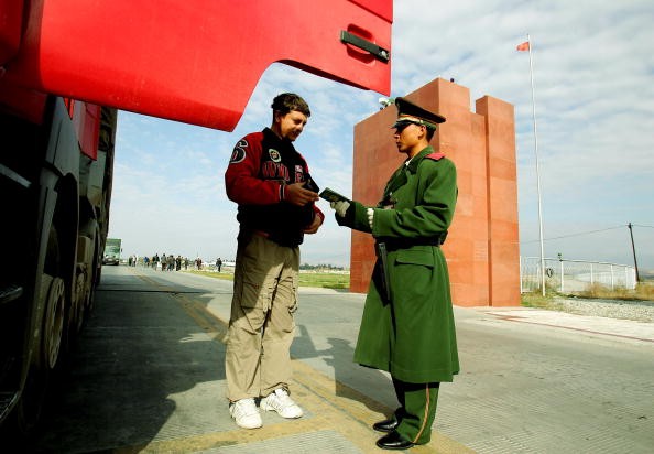 A police officer checks a truck driver's passport at Horgas land port between China and Kazakhstan, Oct. 17, 2005, in Horgas, Xinjiang Uyghur Autonomous Region, China.
