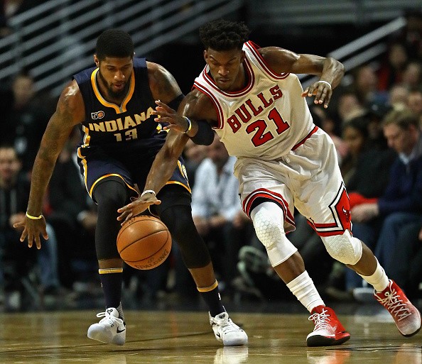 Jimmy Butler of the Chicago Bulls and Paul George of the Indiana Pacers chase down a loose ball at the United Center on December 26, 2016 in Chicago, Illinois.