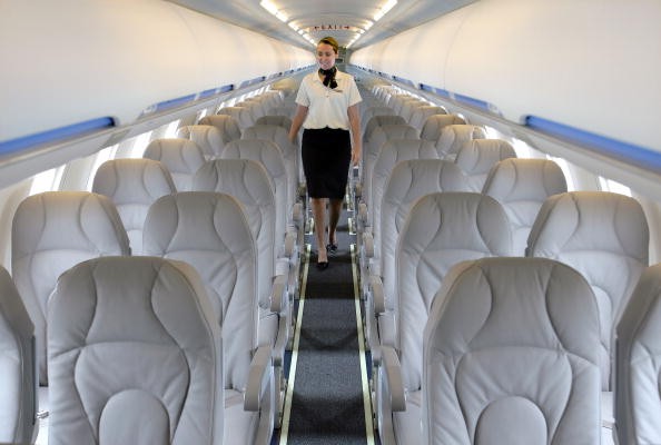 A flight attendant walks through a CRJ900 regional passenger plane.