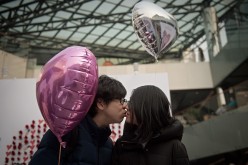 A couple kiss as they walk around a shopping mall on Valentine's Day in Beijing.