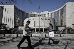Pedestrians walk in front of the People's Bank of China headquarters in Beijing. 