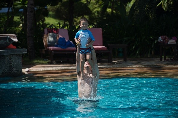 A man lifts a boy up in the air in a pool at the Club Med resort in Sanya, which was bought by Fosun in 2015.