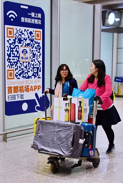 Two Chinese women arrive at Beijing Capital International Airport as they cart purchased goods from abroad.