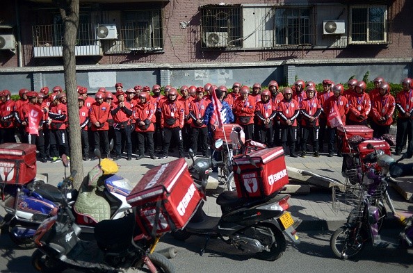 A group of food delivery drivers line up as they prepare for work along a street in Beijing.