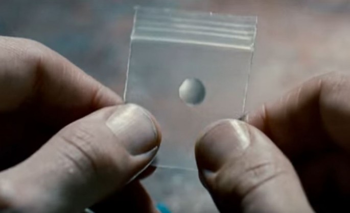 A transparent pill from the movie 'Limitless' is being held by the hand.