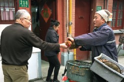 A man (R) sells live birds on the streets of Shanghai in January 2017, an act that has been prohibited amid the spread of the H7N9 avian flu virus. 