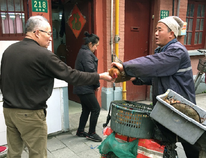 A man (R) sells live birds on the streets of Shanghai in January 2017, an act that has been prohibited amid the spread of the H7N9 avian flu virus. 