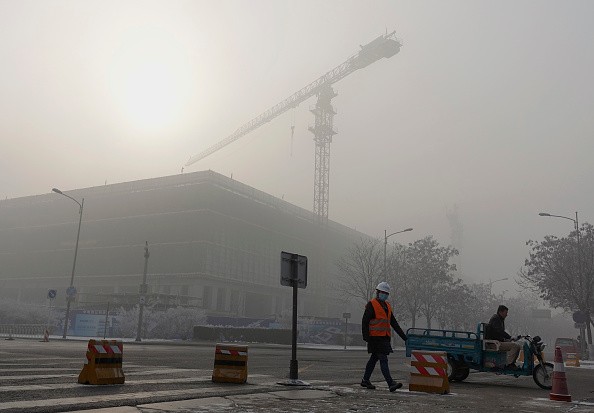 A construction worker walks in the smog in Beijing, China.
