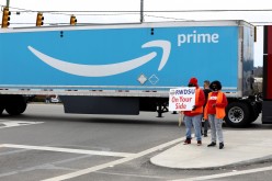 People hold a banner at the Amazon facility as members of a congressional delegation arrive to show their support for workers 