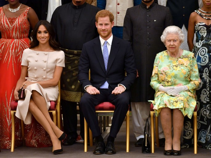 Britain's Queen Elizabeth, Prince Harry and Meghan, the Duchess of Sussex pose for a picture with some of Queen's Young Leaders
