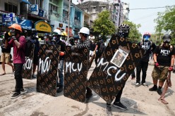 Demonstrators stand behind makeshift shields during an anti-coup protest in Yangon, Myanmar,