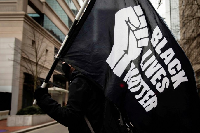 A protester carries a "Black Lives Matter" flag during a demonstration as jury selection begins in Minneapolis