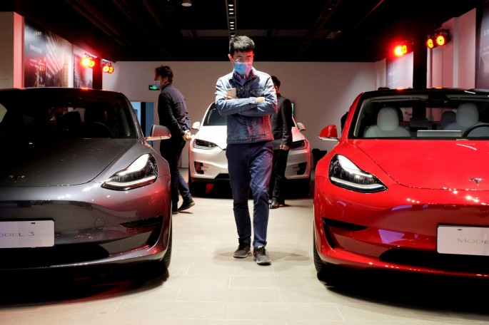 A man wearing a face mask following the coronavirus disease (COVID-19) outbreak walks by Tesla Model 3 sedans and Tesla Model X