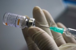 A health worker holds a syringe and a vial of the Sinovac coronavirus disease (COVID-19) vaccine at a market 