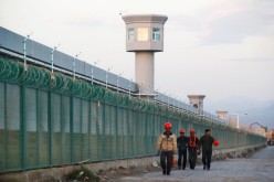 Workers walk by the perimeter fence of what is officially known as a vocational skills education centre