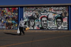  A pedestrian walks past community murals painted on the side of what was the Lake Street Kmart,