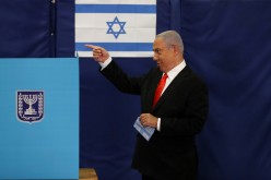  Israeli Prime Minister Benjamin Netanyahu gestures while standing near a voting booth as he prepares to cast his ballot in Israel's general election, at a polling station in Jerusalem