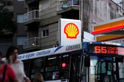 People walk as a bus passes a Shell gas station in Buenos Aires, Argentina, 