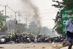 Demonstrators hide behind a barricade during protests against the military coup in Yangon, Myanmar March 28, 2021 in this screen grab 