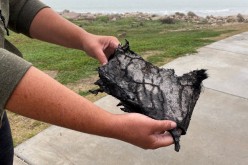 A spectator holds a piece of debris which was blown 5 miles (8 km) from the site where SpaceX test rocket SN11 exploded upon landing,