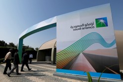 The logo of Aramco is seen as security personnel walk before the start of a press conference by Aramco at the Plaza Conference Center in Dhahran,