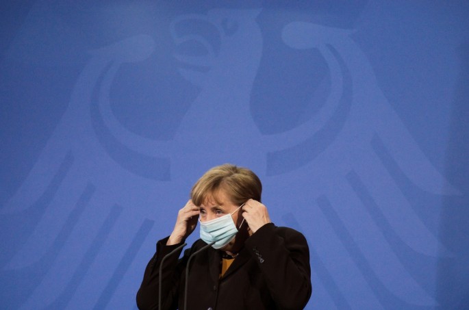 German Chancellor Angela Merkel puts on her face mask as she briefed the media after a virtual meeting with federal state governors