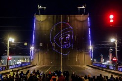 Spectators watch a projection of Yuri Gagarin's portrait to mark the 60th anniversary of the first human space flight in Saint Petersburg, Russia