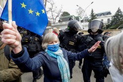 A woman holds an EU flag next to police officers during a protest over the Russian intelligence services alleged involvement in an ammunition depot explosion in Vrbetice area in 2014,