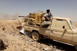  A Yemeni government fighter fires a vehicle-mounted weapon at a frontline position during fighting against Houthi fighters in Marib, Yemen