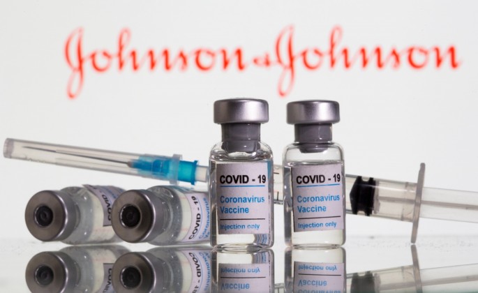 Vials labelled "COVID-19 Coronavirus Vaccine" and sryinge are seen in front of displayed Johnson&Johnson logo in this illustration taken
