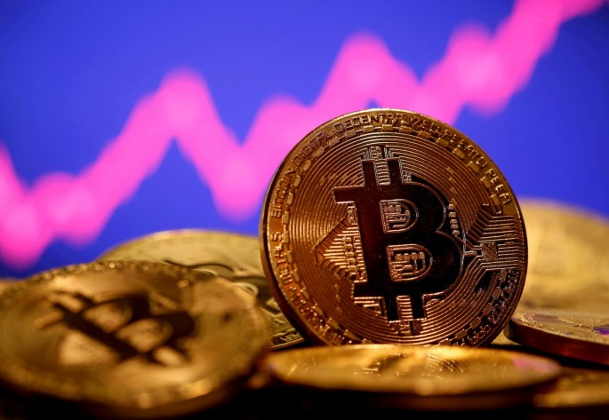 A representation of virtual currency Bitcoin is seen in front of a stock graph in this illustration