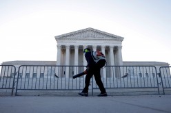 A worker clears front steps as morning rises over the U.S. Supreme Court building, still closed to the public during the COVID-19 pandemic, in Washington, U.S.