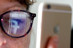The Facebook logo is reflected on a woman's glasses in this photo illustration taken