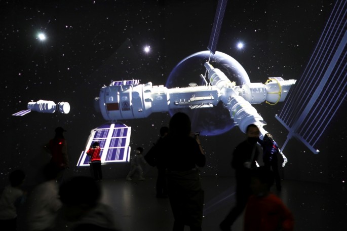 Visitors stand near a giant screen displaying the images of the Tianhe space station at an exhibition featuring the development of China's space exploration on the country's Space Day