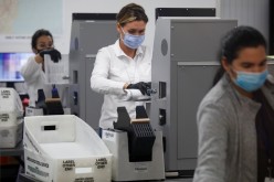 Workers of the Miami-Dade County Elections Department feed mail-in ballots in counting machines during the 2020 U.S. presidential election in Miami, Florida, U.S.,