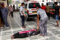 A man tries to lift a woman that fainted after seeing the body of a relative who died from the coronavirus disease (COVID-19), at a crematorium in New Delhi, India