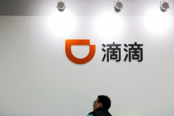 A man is seen under a Didi logo at the headquarters of Didi Chuxing in Beijing, China