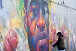 A man places flowers at a mural of George Floyd after the verdict in the trial of former Minneapolis police officer Derek Chauvin, found guilty of the death of Floyd, in Denver