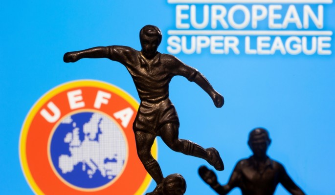 Metal figures of football players are seen in front of the words "European Super League" and the UEFA logo in this illustration taken
