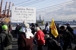 Shell Oil Company's drilling rig Polar Pioneer is seen in the background as activists march to the entrance of Terminal 5 to protest the rig which is parked at the Port of Seattle, Washington