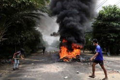 An anti-coup protester walks past burning tires after activists launched a 