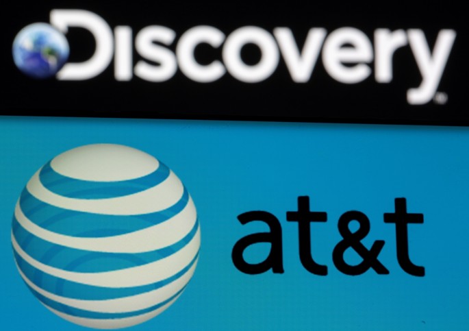 AT&T logo is seen on a smartphone in front of displayed Discovery logo in this illustration